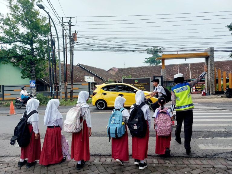 Wujud Kepedulian, Polisi Bantu Siswa SD Menyeberang Jalan dengan Aman